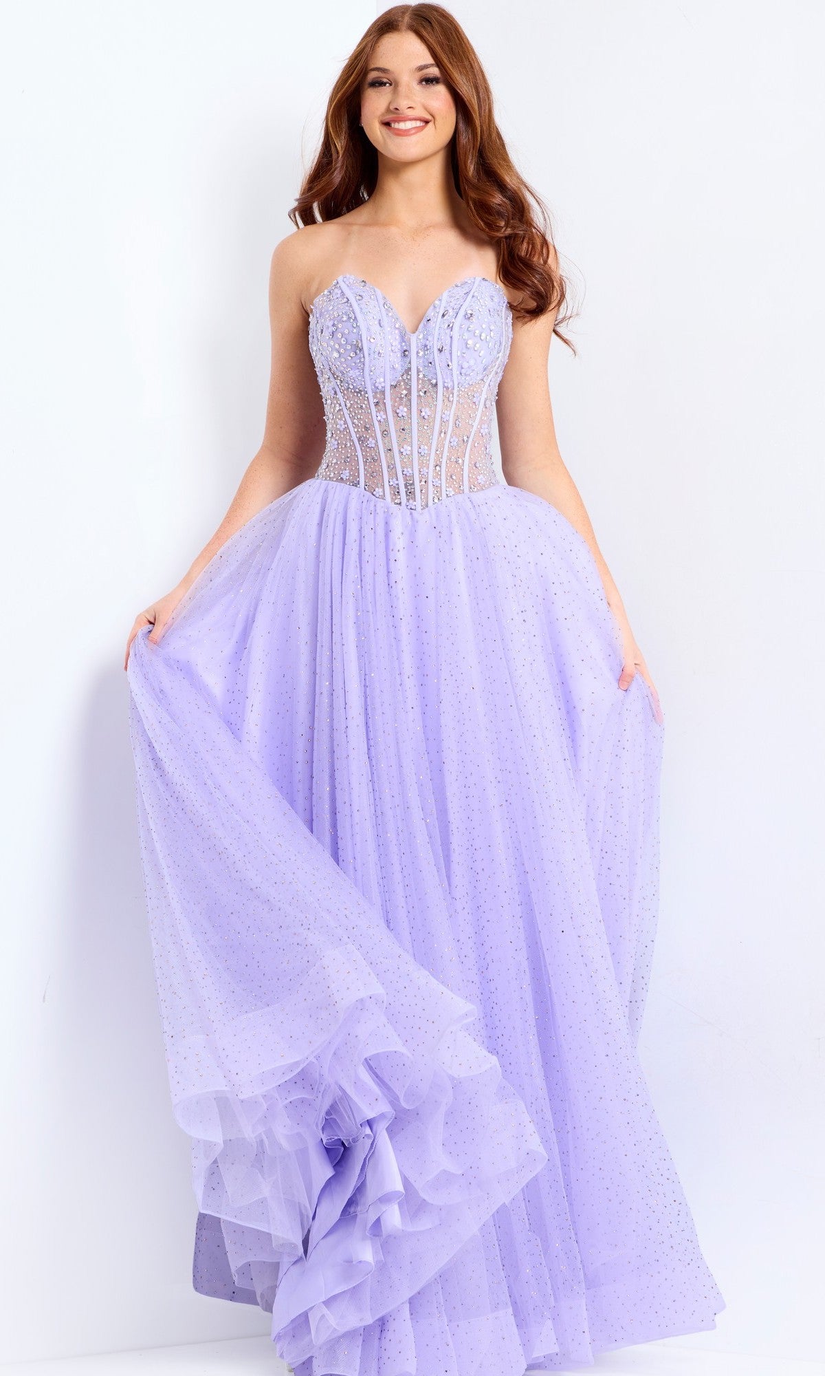 Wearing the Jovani 48309 long prom dress with a strapless corset bodice and full sparkly tulle skirt, a woman smiles as she holds out the sides of her gown.